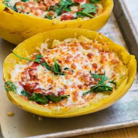 lasagna in a spaghetti squash with spinach and melted cheese on a baking sheet