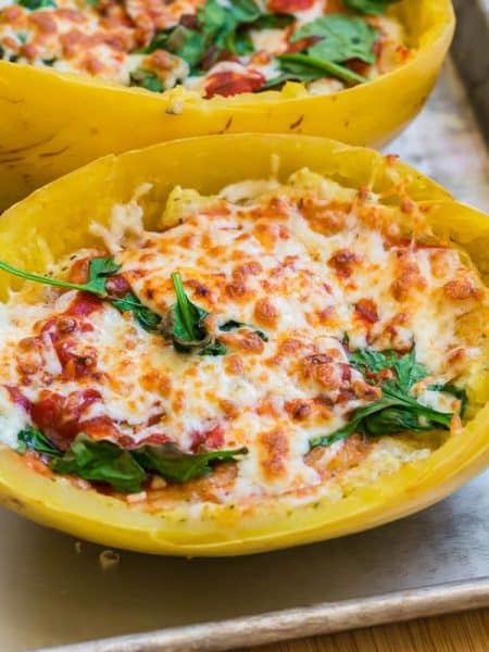 lasagna in a spaghetti squash with spinach and melted cheese on a baking sheet