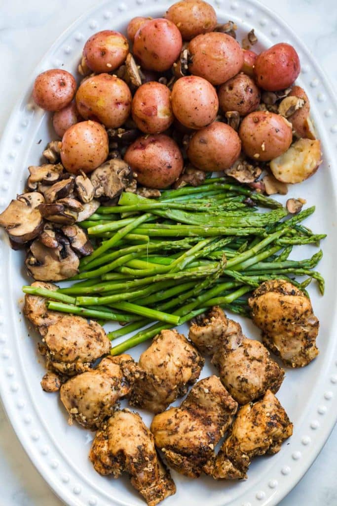 white platter with cooked chicken thighs, green beans and potatoes