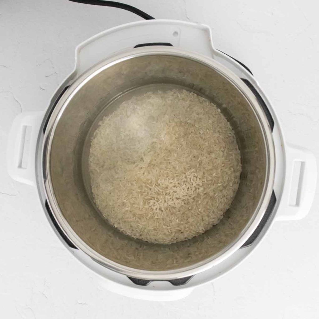 top down view of an instant pot with white rice and water