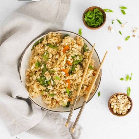 Vegetable fried rice on a white counter with chopsticks resting on the right side of the bowl.