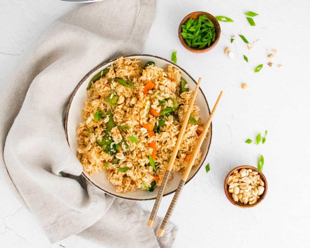 bowl of cooked fried rice with chopsticks resting on the side on the right side of the bowl
