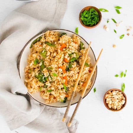 bowl of cooked fried rice with chopsticks resting on the side on the right side of the bowl