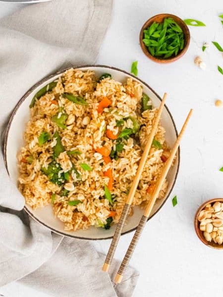 bowl of cooked fried rice with chopsticks resting on the side on the right side of the bowl