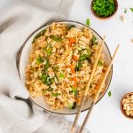 bowl of cooked fried rice with chopsticks resting on the side on the right side of the bowl