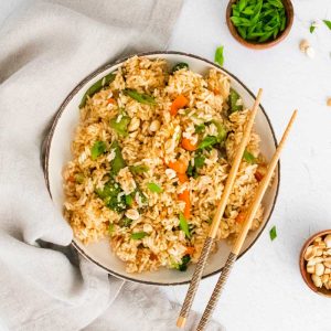 bowl of cooked fried rice with chopsticks resting on the side on the right side of the bowl
