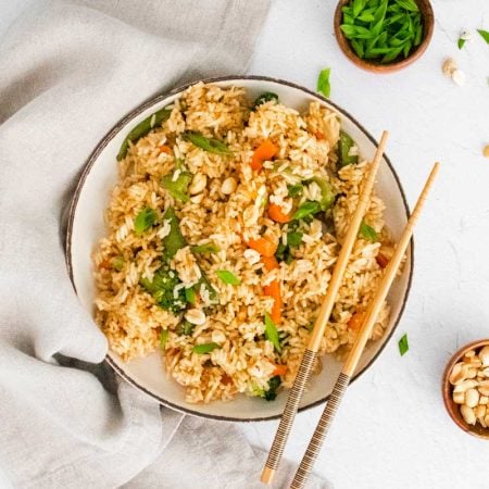 bowl of cooked fried rice with chopsticks resting on the side on the right side of the bowl