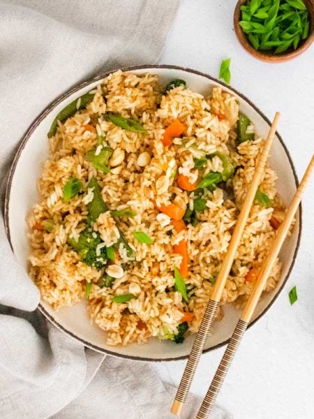 bowl of cooked fried rice with chopsticks resting on the side on the right side of the bowl