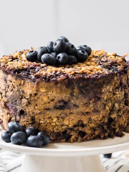 baked oatmeal on cake stand topped with fresh blueberries