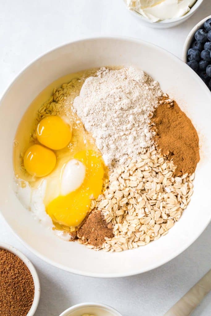 white mixing bowl eggs, oats, and cinnamon to make Blueberry Oatmeal Bake