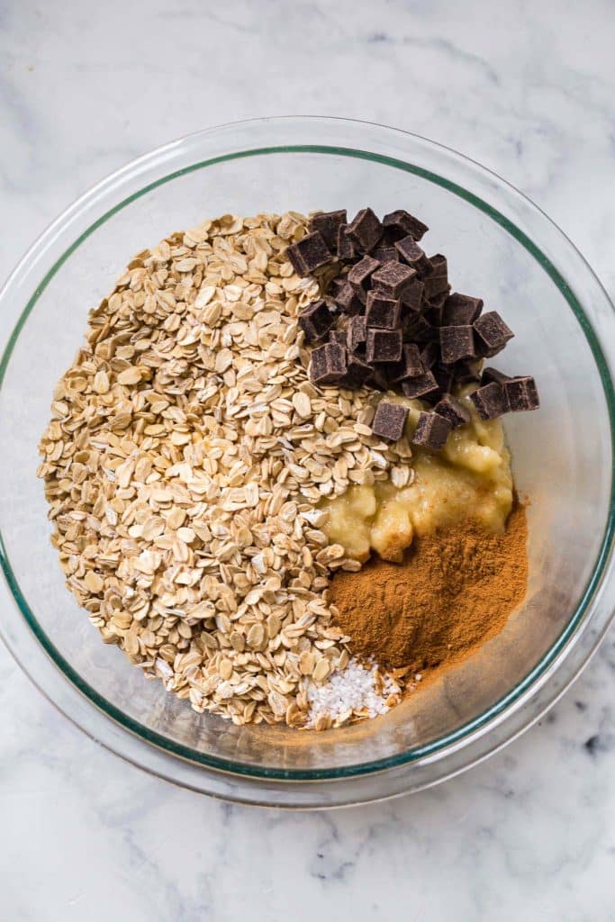 glass mixing bowl with oats, chocolate chips, mashed bananas and spices