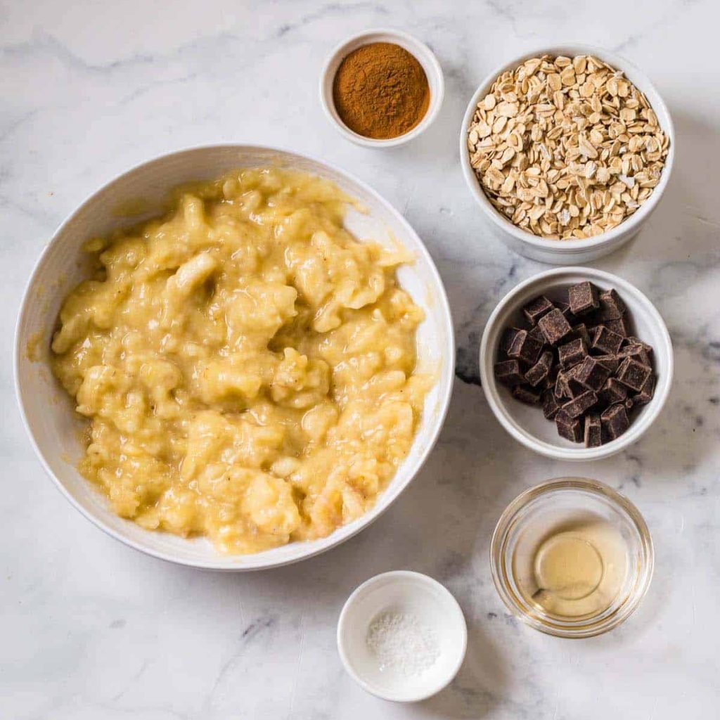 6 bowls with ingredients to make banana oatmeal bites