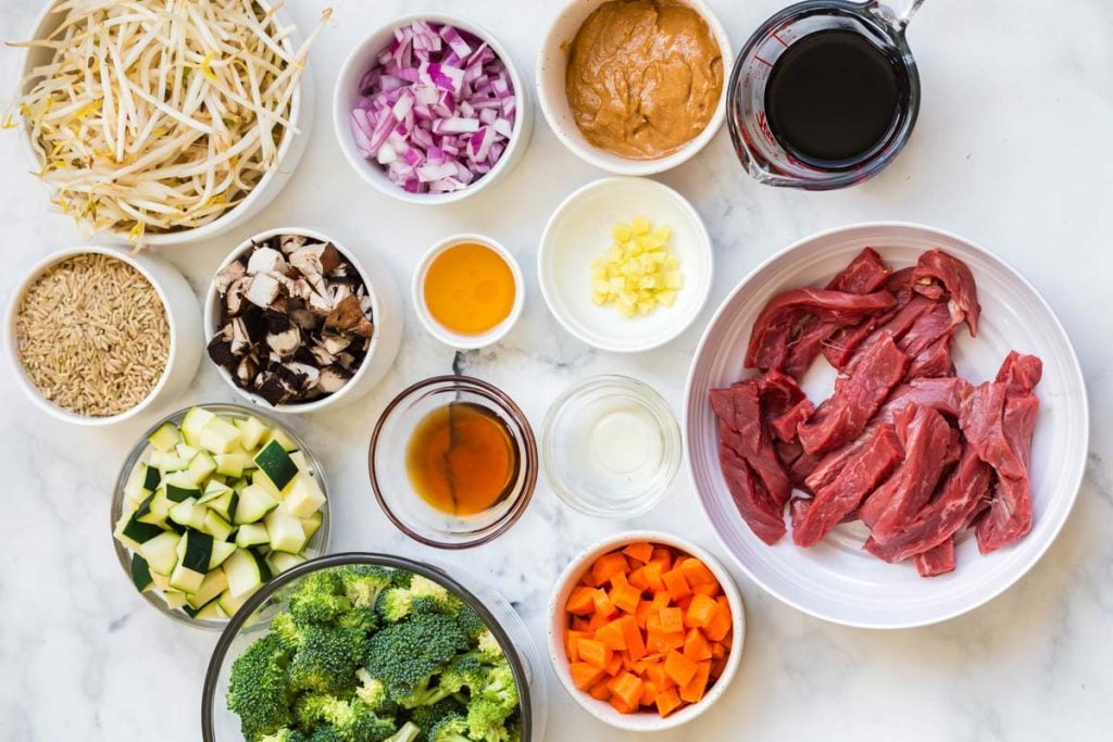 bowls of ingredients for Beef Stir Fry on top of a marble counter top