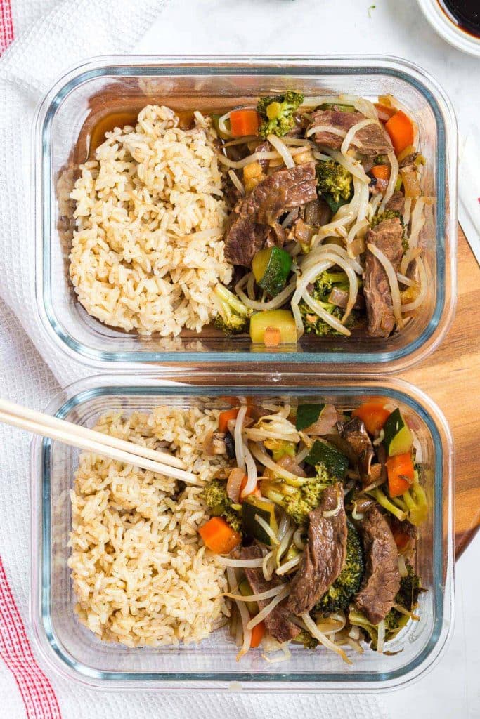 two glass meal prep containers side by side, filled with beef stir fry and vegetables