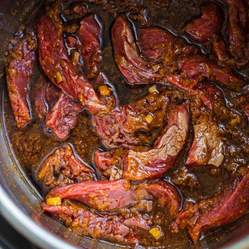 top down view of open Instant Pot with steak slices and sauce