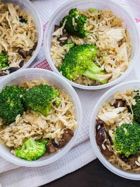four containers with rice and chicken and broccoli shown from above