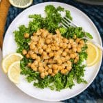 white plate with lemon slices and a bed of kale topped with chickpea salad