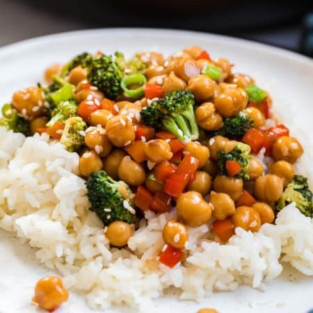 close up image of white plate with bed of white rice topped with a chickpea and broccoli mixture