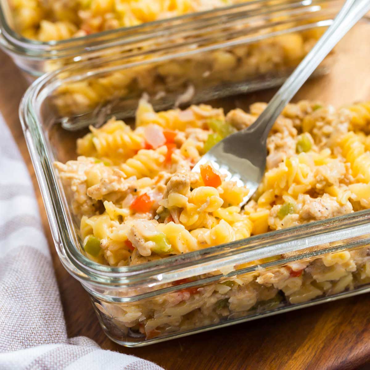 Philly Cheesesteak Pasta inside glass meal prep dish with fork scooping up a bite. 