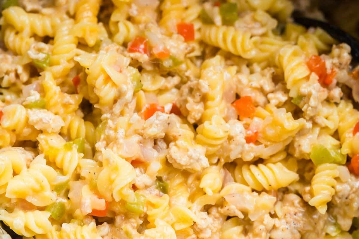 Cooked rotini pasta inside an instant pot and mixed together with bell peppers, ground turkey, cheese and other seasonings.
