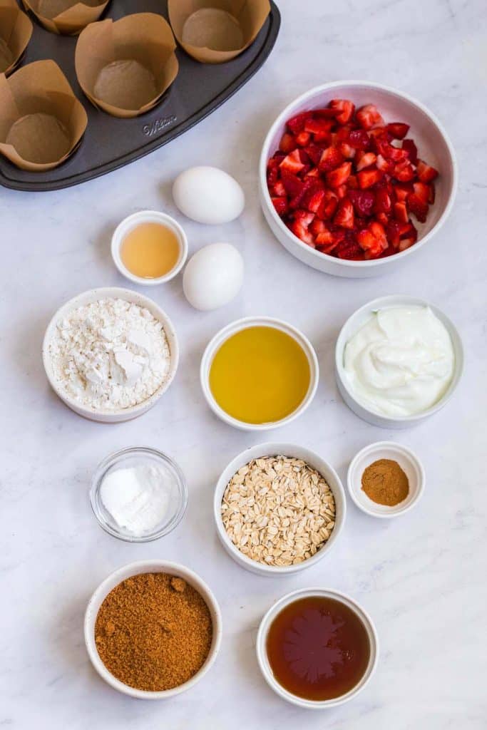 ingredients in strawberry muffins, in small white bowls on white countertop
