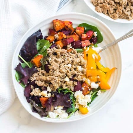 top down view of salad on a white plate. Salad has ground turkey, roasted sweet potatoes, fresh peppers, cheese, and spring mix