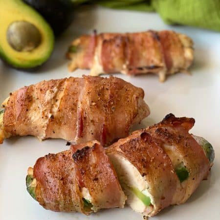 close up of bacon wrapper chicken with avocado stuffed inside.