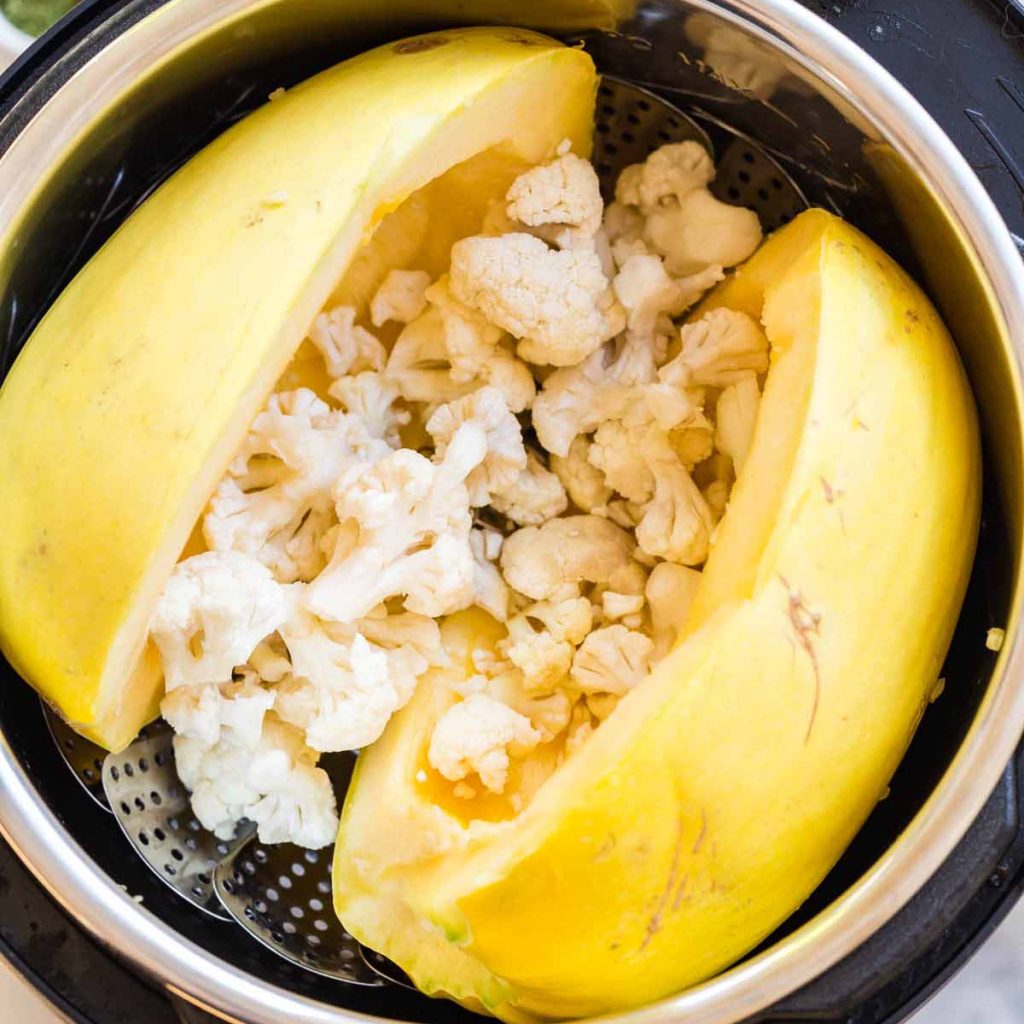 image of two spaghetti squash halves inside an instant pot and stuffed with cauliflower florets