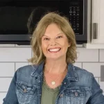 Becca, author of My Crazy Good Life, standing in kitchen smiling.