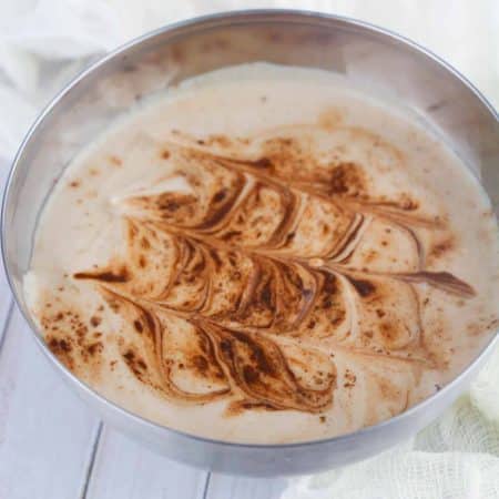 Silver bowl with decorated mocha flavored yogurt inside.