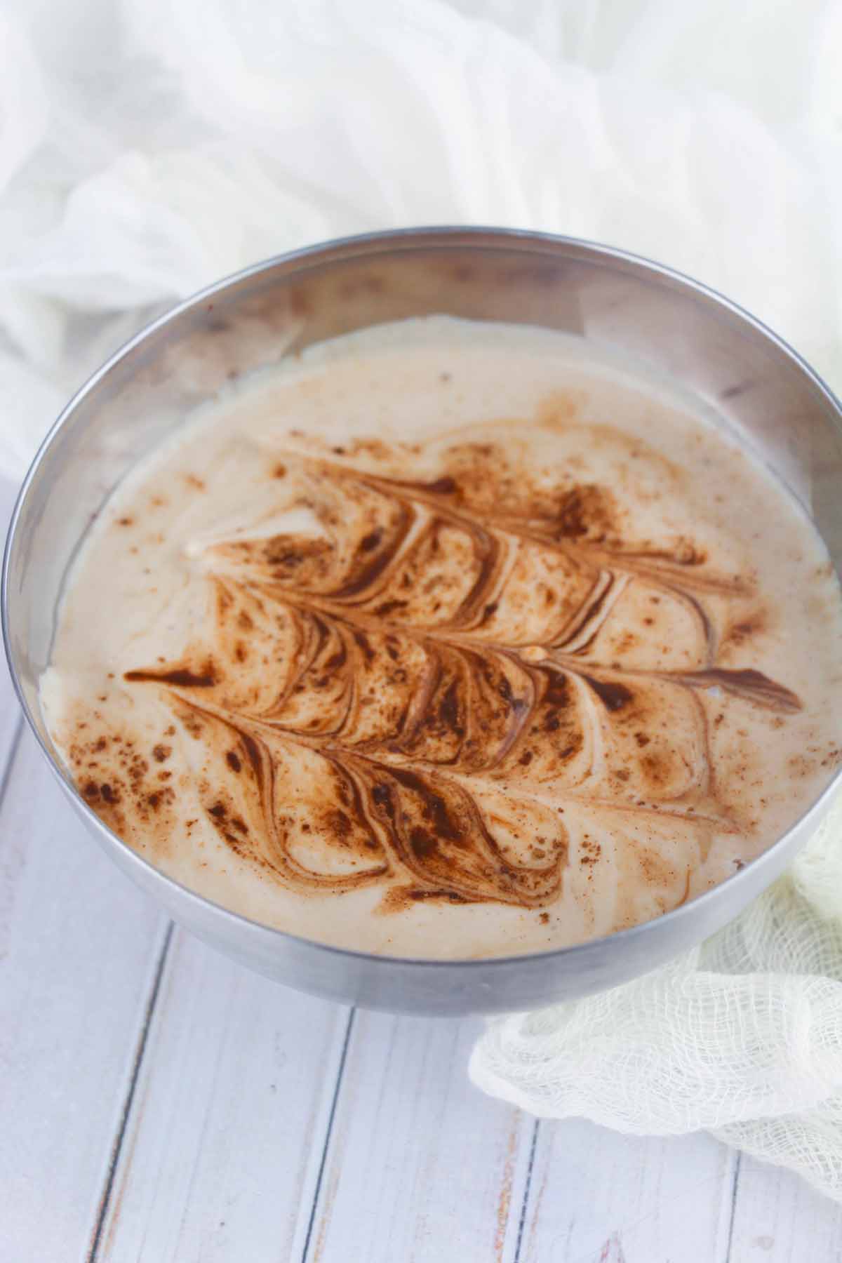 Silver bowl with decorated mocha flavored yogurt inside.
